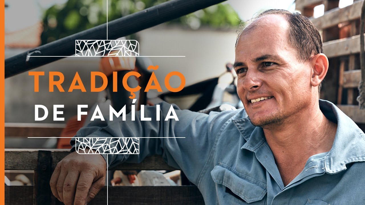 Homem sorrindo encostado em uma caminonete com escrita "TRADIÇÃO DE FAMíLIA"